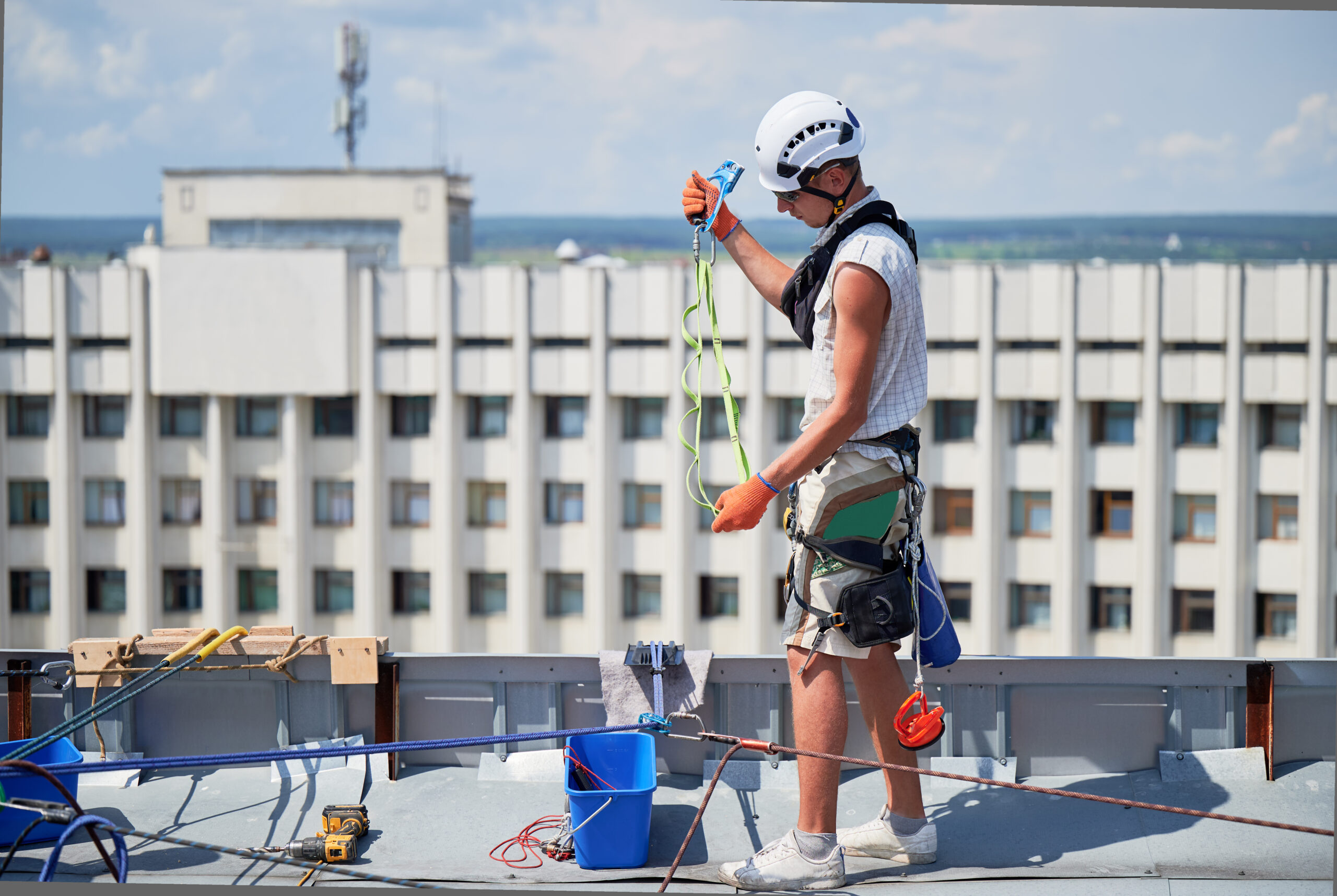 Industrial mountaineering worker cleaning window outside building.